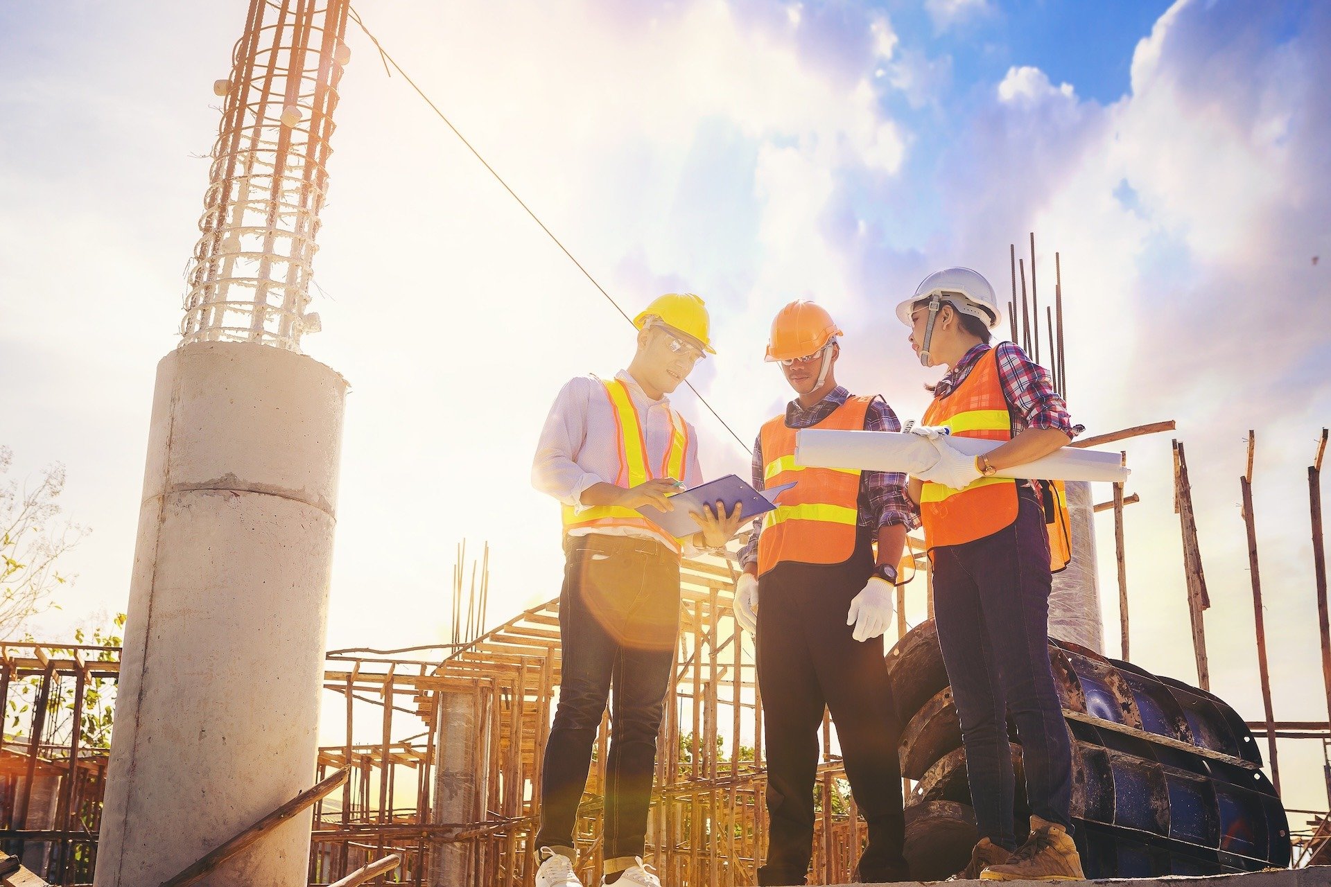 three people in protective gear looking at plans on a work site