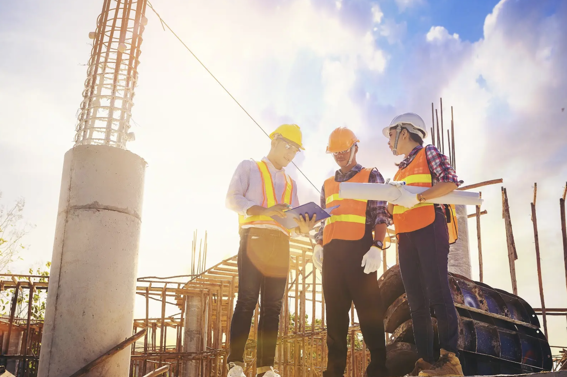 Three construction workers discussing plans around a tablet on a construction site