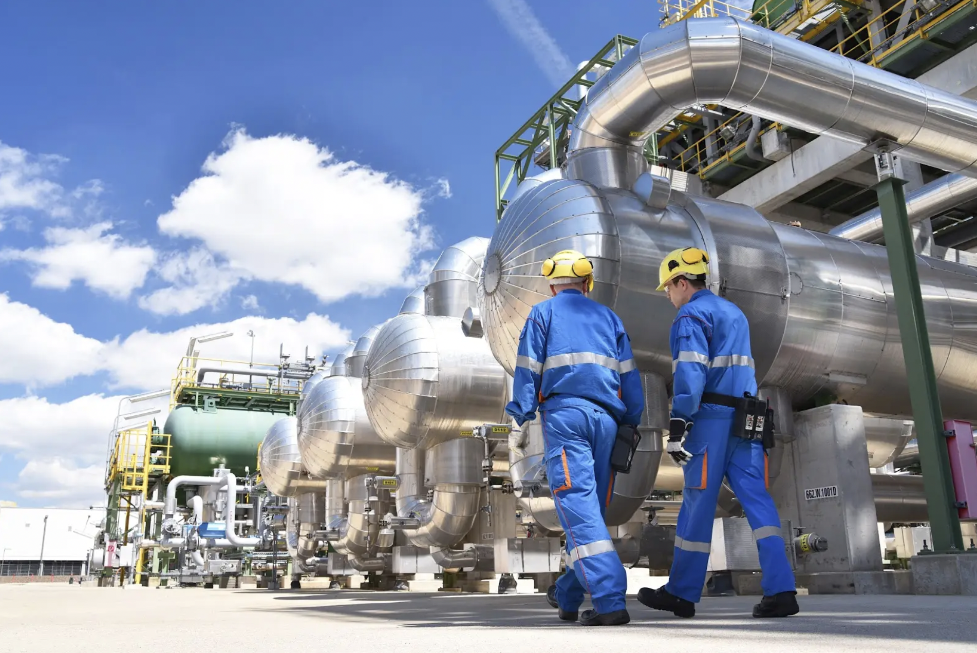 Workers in safety gear walking at production and processing oil plant