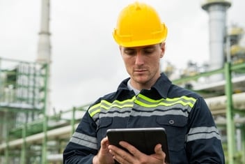 Refinery oil engineer worker in protection hardhat with digital tablet 