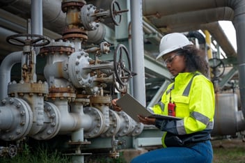 Engineers or industrial worker at large metal pipelines and valve systems